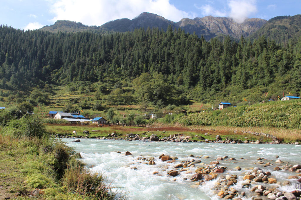 Fluss in Nepal mit Dorf und Bergen im Hintergrund als Beispiel für Wasserkraft