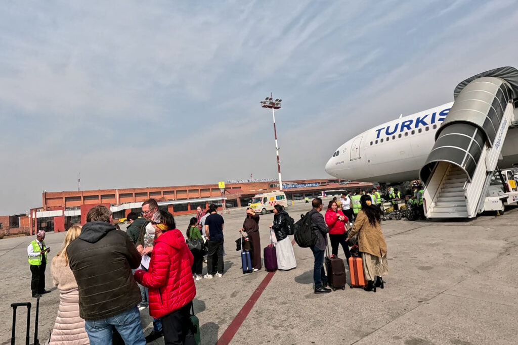 Ankunft am Tribhuvan Airport – Warten auf den Shuttlebus Reisende stehen am Tribhuvan Airport in Kathmandu auf dem Rollfeld und warten auf den Bus zum Terminal