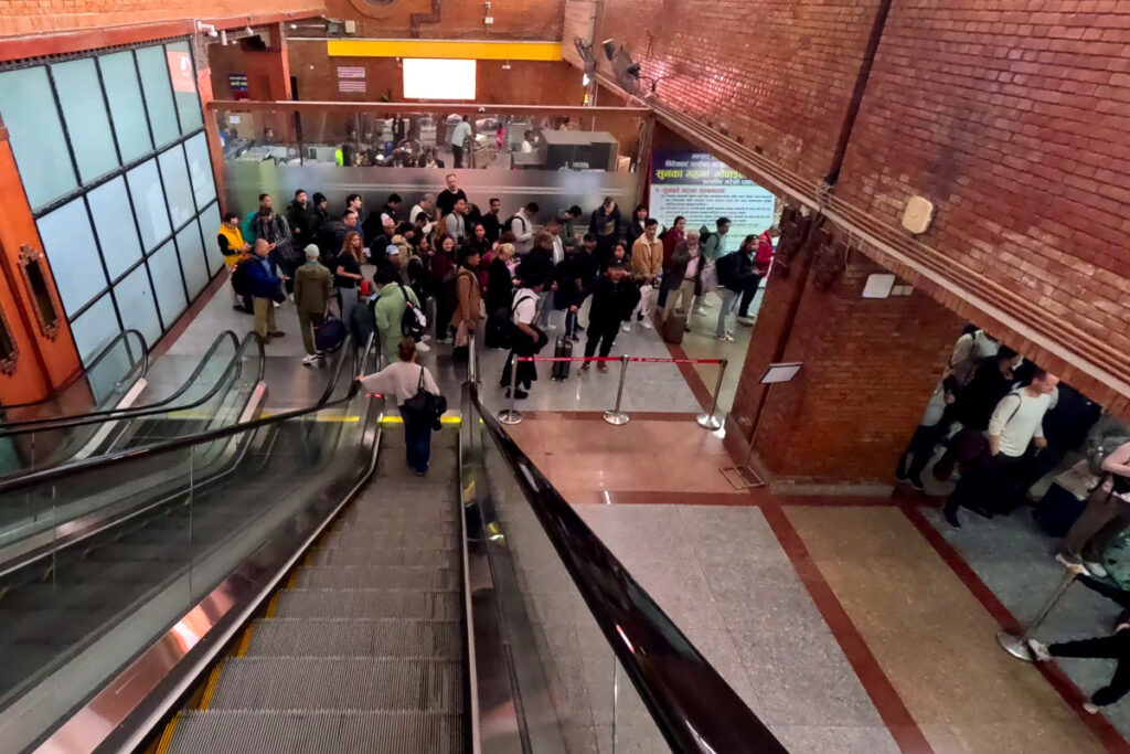 Schlange nach der Immigration am Tribhuvan Airport Reisende fahren am Tribhuvan Airport in Kathmandu mit der Rolltreppe nach unten und sehen eine lange Schlange vor der Sicherheitskontrolle