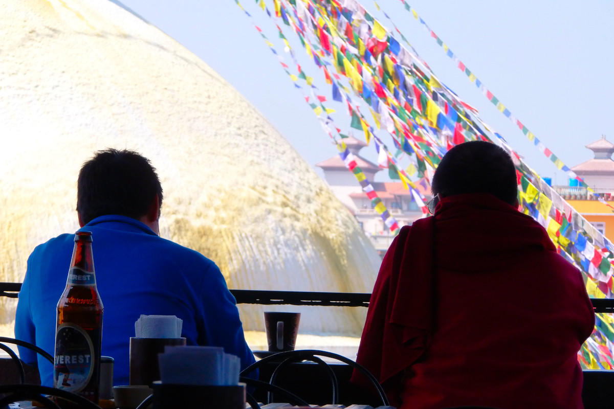 Gäste auf einer Dachterrasse mit direktem Blick auf den Boudhanath Stupa und die Gebetsfahnen