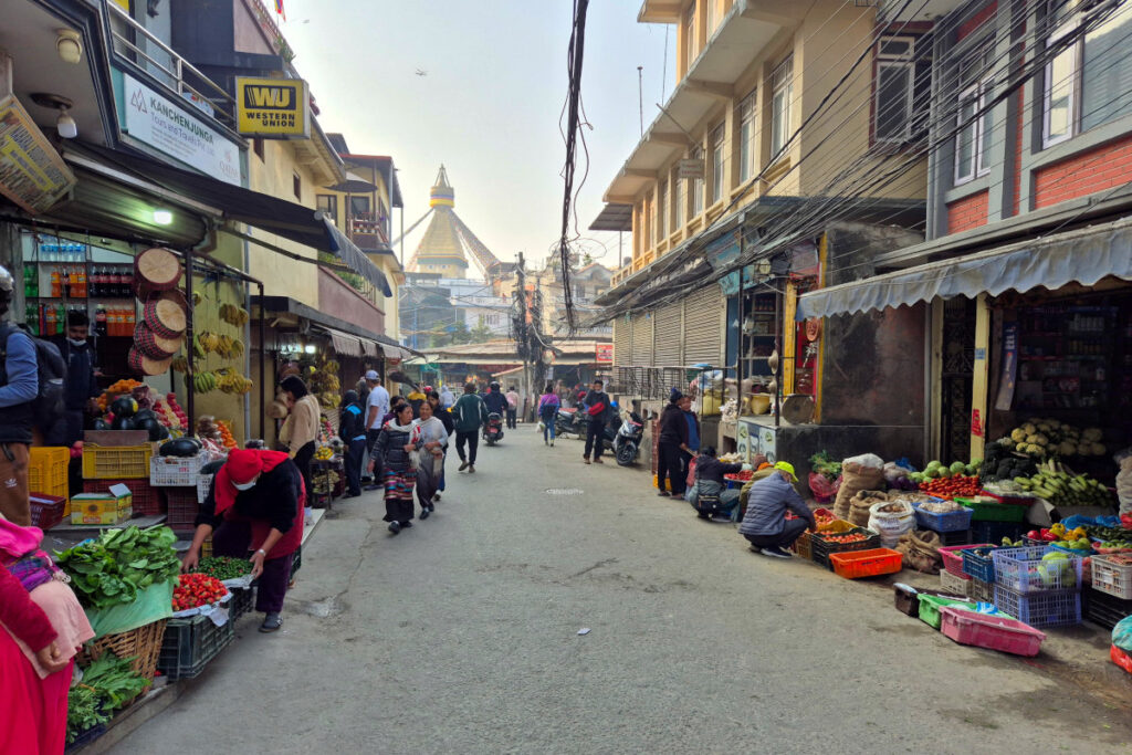 Gassen rund um den Boudhanath Stupa Belebte Gasse mit Gemüseständen und Blick auf den Boudhanath Stupa in Kathmandu