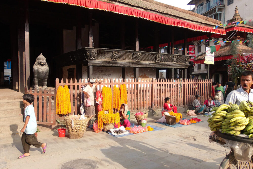 Blumenverkäufer und Marktstände vor einem Tempel in Kathmandus Altstadt