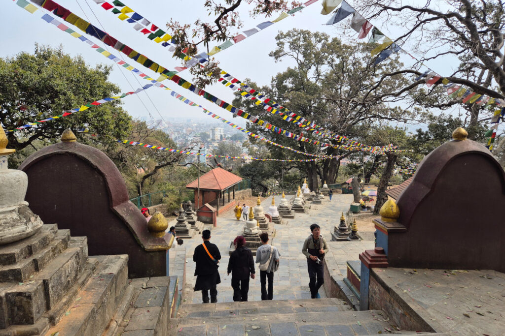 Besucher zwischen kleinen Stupas und Gebetsfahnen auf dem Gelände von Swayambhunath