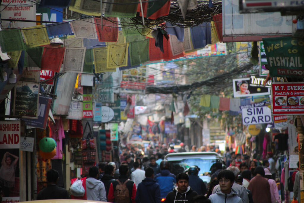 Belebte Gasse in Thamel mit Fußgängern, Geschäften und Verkehr