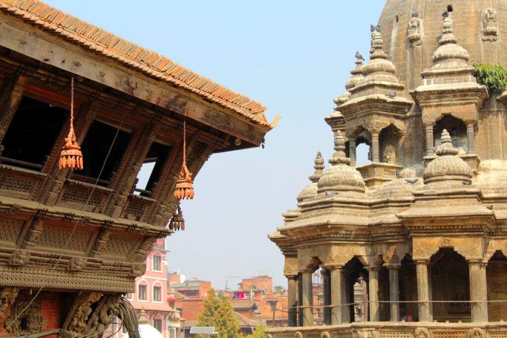 Krishna Mandir und traditionelle Holzarchitektur Steinerner Krishna Mandir neben einer reich geschnitzten Holzfassade am Patan Durbar Square